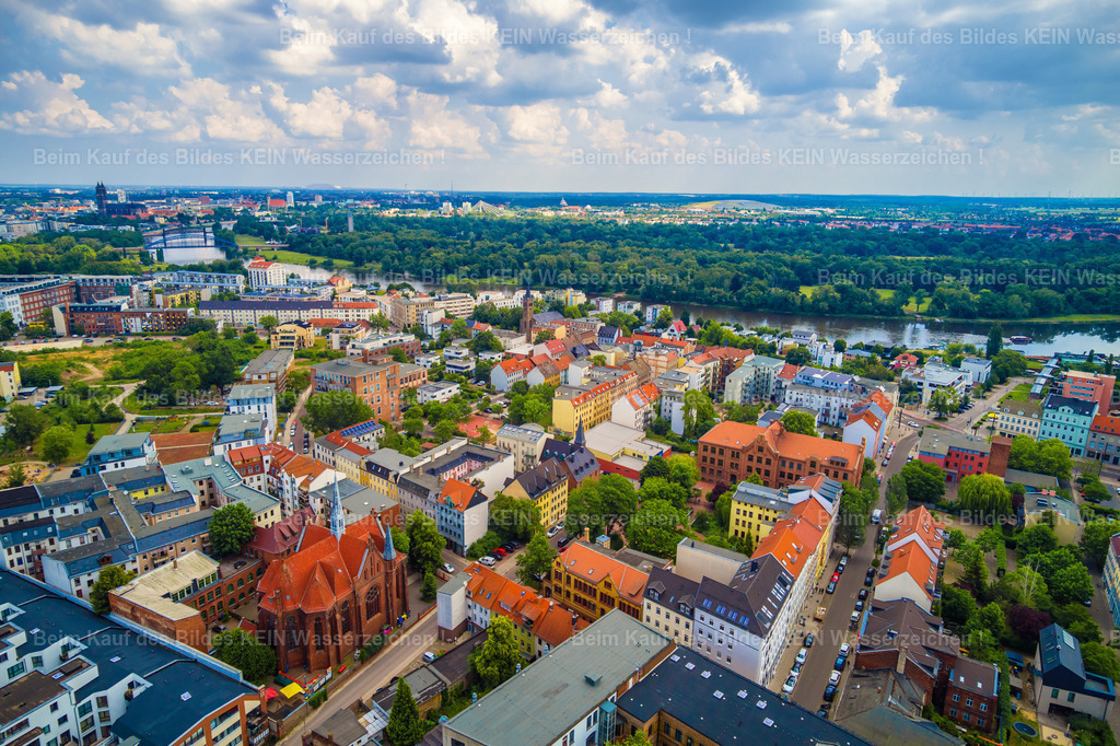 Magdeburg Buckau Kirche St Norbert Karl-Schmidt-Straße Thiemstraße Schönebecker-0027 | Buckau ist ein Stadtteil mit einem ganz eigenen Charakter. Zwischen Coquistraße und Schönebecker Straße liegen enge Straßenzüge, historische Wohnhäuser und ehemalige Industrieareale dicht beieinander. Wer hier unterwegs ist, entdeckt an vielen Stellen noch die Spuren einer Zeit, in der Wohnen und Arbeiten unmittelbar zusammengehörten. –  –  Im 19. Jahrhundert entwickelte sich Buckau vom kleinen Dorf zu einem bedeutenden Industriestandort und zu einer Wiege des deutschen Maschinenbaus. Mit den Fabriken wuchs der Stadtteil, und für die Arbeiter entstanden dicht bebaute Wohnviertel. Die repräsentativen Fassaden der Gründerzeit erzählen bis heute von dieser Entwicklung. Manchmal lagen Werkstätten und Fabrikhallen nur wenige Schritte von den Haustüren entfernt. –  –  Heute hat sich Buckau stark verändert. Viele ehemalige Industrieflächen wurden neu genutzt, alte Gebäude saniert und neue Wohnhäuser ergänzt. Trotzdem ist die Vergangenheit noch immer Teil des Stadtbildes. Gerade diese Mischung aus Geschichte, gewachsenen Straßen und neuem Leben macht den besonderen Reiz des Stadtteils aus. –  –  Wenn ich Buckau von oben betrachte, wird dieser Zusammenhang besonders deutlich. Man erkennt, wie eng die Wohnviertel einst mit den Industrieanlagen verwoben waren und wie sich daraus ein Stadtteil entwickelt hat, der heute ganz unterschiedliche Lebenswelten verbindet. Für mich sind solche Aufnahmen mehr als ein Blick auf Gebäude – sie erzählen ein Stück Magdeburger Heimatgeschichte. - Realisiert mit Pictrs.com