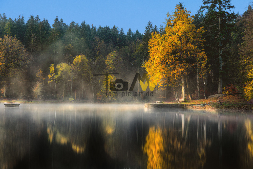 Schöner herbstlicher Sonnenaufgang|Dunst am stillen Ebnisee | Das Bild zeigt den Ebnisee, den größten See im Schwäbischen Wald, gelegen zwischen Althütte und Kaisersbach im Rems-Murr-Kreis. Der künstlich angelegte Stausee diente ursprünglich der Flößerei von Brennholz nach Stuttgart. Heute ist er ein beliebtes Ausflugsziel für Naherholung mit Bademöglichkeiten, Bootsverleih, Grillplätzen und Wanderwegen. Der See hat eine Fläche von etwa 6,3 bis 6,7 Hektar und eine maximale Tiefe von 4,75 Metern.  - Realisiert mit Pictrs.com