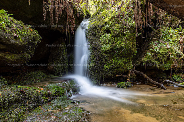 Verborgener Wasserfall im Grünen | Ruhige Naturaufnahme eines kleinen Wasserfalls, der weich in ein klares Becken fließt. Das grüne Umfeld, die Felsen und die lange Belichtungszeit erzeugen eine friedliche, fast märchenhafte Stimmung. - Realisiert mit Pictrs.com