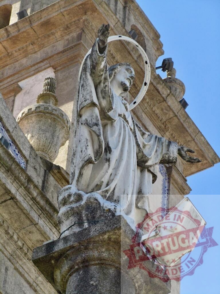 Jesus Christ statue on a historic church exterior | Stone statue of Jesus Christ with a halo on an old church against a blue sky - Realized with Pictrs.com