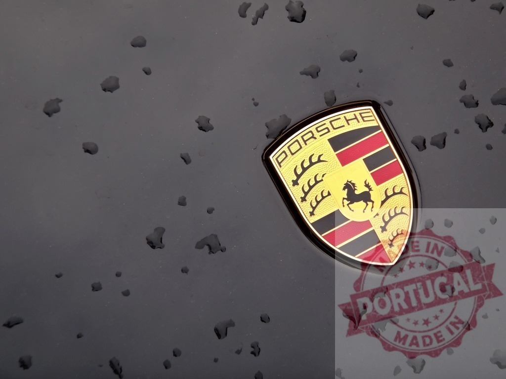 Porsche crest on black car hood with raindrops | Porsche crest emblem on a wet black luxury sports car hood with water drops - Realisiert mit Pictrs.com