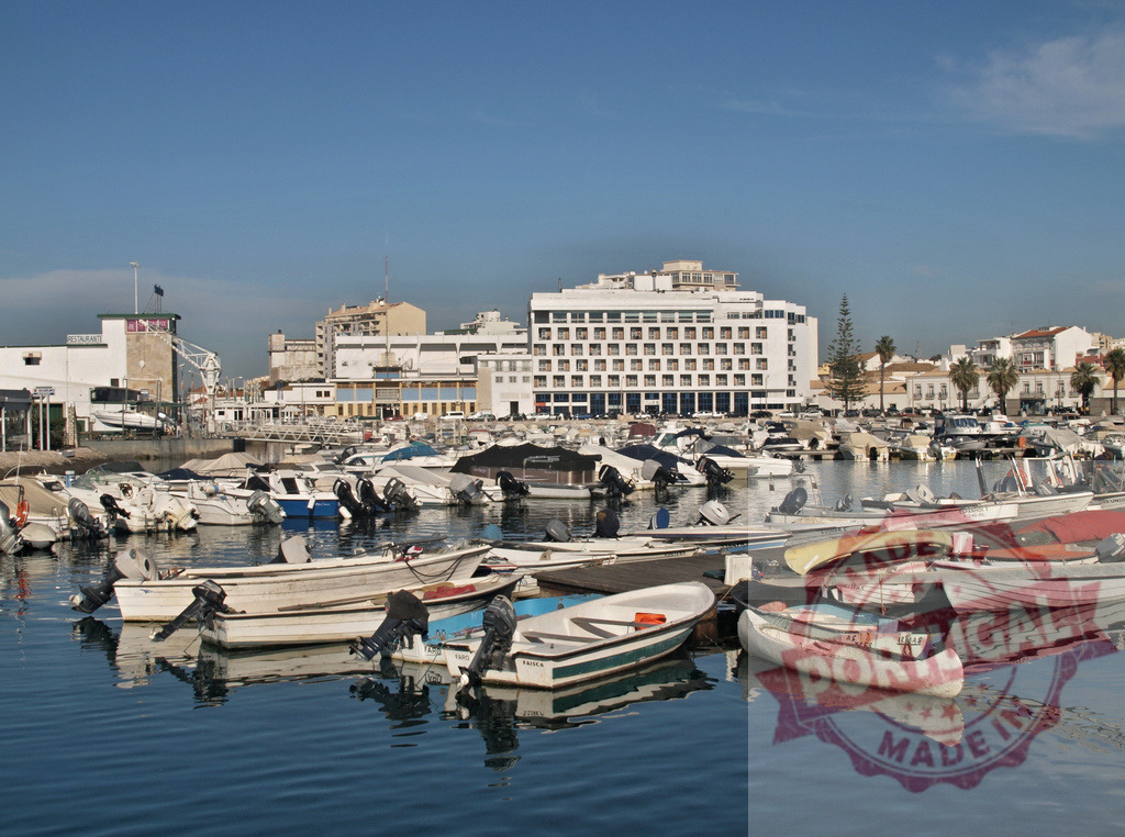 Faro marina with boats and city skyline | Boats moored in the marina with city buildings and a hotel reflecting on the water - Realized with Pictrs.com