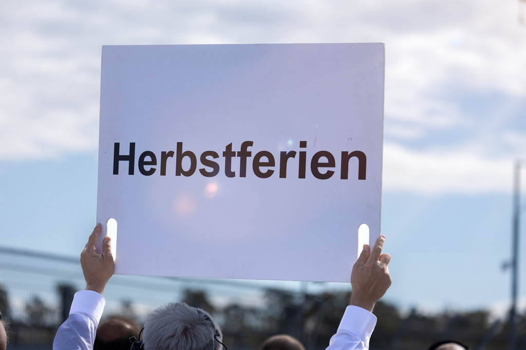 HERBSTFERIEN auf einem Schild | Ein Schild mit dem Text HERBSTFERIEN wird in die Höhe gehalten - Realisiert mit Pictrs.com