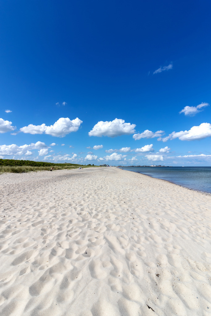 Wandbild: Sandstrand in Weidefeld an der Ostsee | Dieses Wandbild im Hochformat zeigt den traumhaften Ostseestrand in Weidefeld. Der Strandsand ist so gut wie frei von Steinen. Am blauen Himmel befinden sich nur einige helle Wolken. - Realisiert mit Pictrs.com