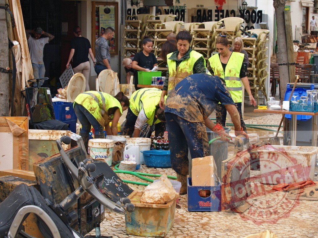 Volunteers cleaning mud after natural disaster flood | Albufeira Flood - discruction by weather problems Volunteers are cleaning mud on a street after a catastrophic flood, showing community support - Realized with Pictrs.com