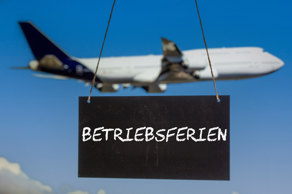 Symbolbild Betriebsferien: Schild mit der Aufschrift BETRIEBSFERIEN vor einem startenden Flugzeug (Composing) | Symbolbild Betriebsferien: Schild mit der Aufschrift BETRIEBSFERIEN vor einem startenden Flugzeug (Composing) - Realisiert mit Pictrs.com