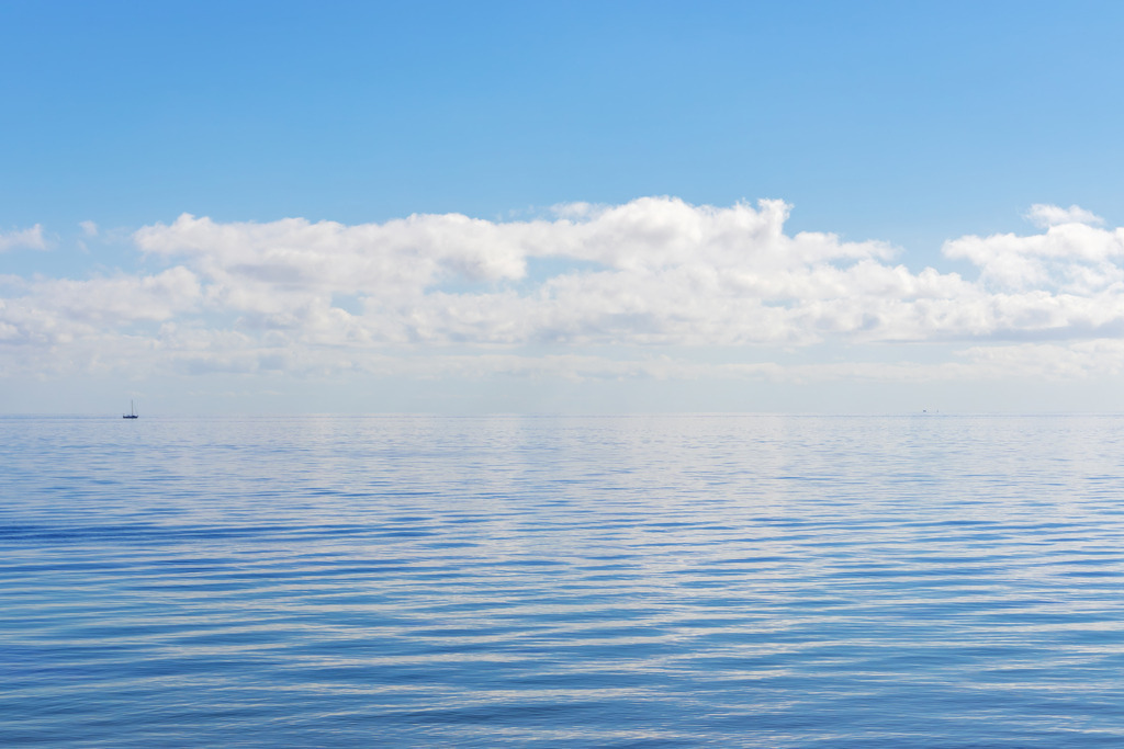 Wandbild: Erhabene Weite mit sanfter Wolkenspiegelung | Bringen Sie die tiefe, klare Ruhe des offenen Meeres in Ihr Zuhause. Dieses maritime Wandbild besticht durch seine kraftvolle blaue Farbpalette und die sanften Lichtreflexe auf der Wasseroberfläche. Ein einsames Segelboot am fernen Horizont unterstreicht die beeindruckende Dimension der Ostsee und lädt dazu ein, den Blick in die Ferne schweifen zu lassen. Ein minimalistisches Kunstwerk, das Ordnung und Gelassenheit in Ihr Wohnzimmer bringt – der perfekte visuelle Ruhepol für eine moderne Wandgestaltung. - Realized with Pictrs.com