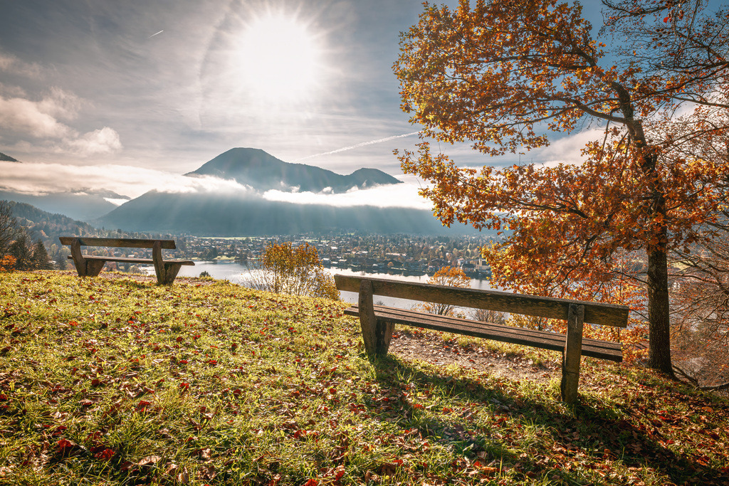Aussicht auf den Tegernsee vom Leeberg aus, über zwei Parkbänke und herbstlicher Atmosphäre hinweg auf den Wallberg | Das Bild zeigt einen Blick vom Leeberg über den herbstlichen Tegernsee in Oberbayern, Deutschland.Im Hintergrund erhebt sich markant der Wallberg (1.723 m) über der Gemeinde Rottach-Egern, der zu den bekanntesten Bergen der Bayerischen Voralpen gehört - Realisiert mit Pictrs.com