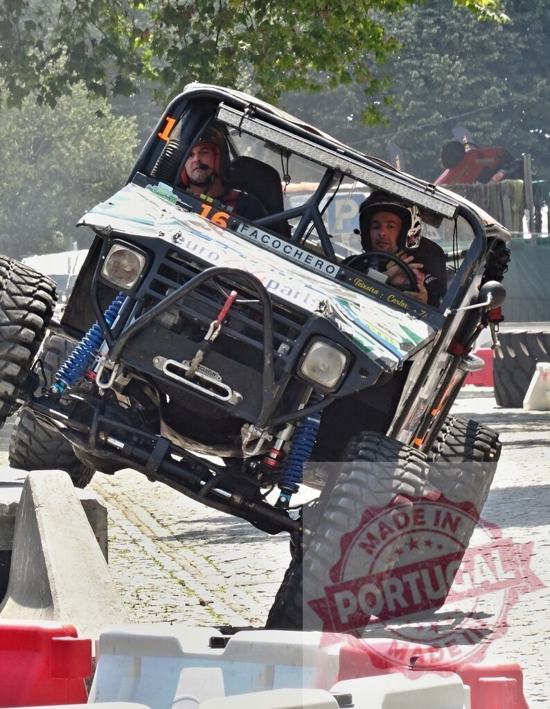 Two pilots driving a 4x4 during an off-road competition | Two pilots are driving a modified 4x4 during an off-road competition, climbing over concrete obstacles - Realized with Pictrs.com