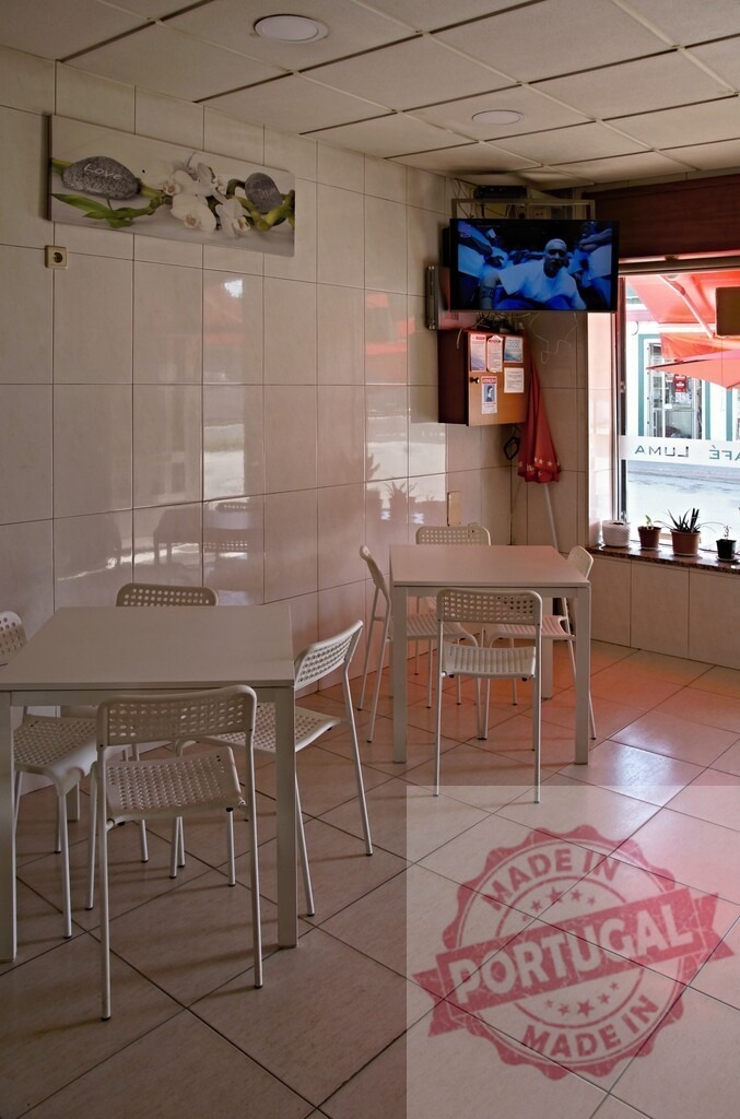 Empty cafe interior featuring modern furniture and television | Clean cafe interior with white tables, chairs, and television screen showing content - Realisiert mit Pictrs.com