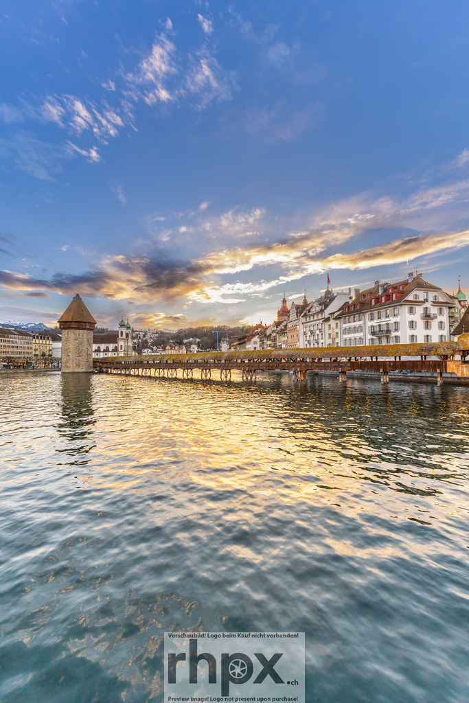 Kapellbrücke Luzern im Abendlicht | Wahrzeichen. Geschichte. Abendgold. Das warme Abendlicht spiegelt sich sanft in der Reuss und lässt das historische Wahrzeichen Luzerns in einem magischen Glanz erstrahlen. Wolken und Wasser verschmelzen vor der Kulisse der Altstadt zu einer Komposition voller Ruhe und Eleganz. Wähle unter "Produktauswahl" dein Wunschformat: Vom klassischen Wandbild über Puzzle &amp; Tassen bis zum digitalen Download (z.B. als Handy-Hintergrund). - Realisiert mit Pictrs.com