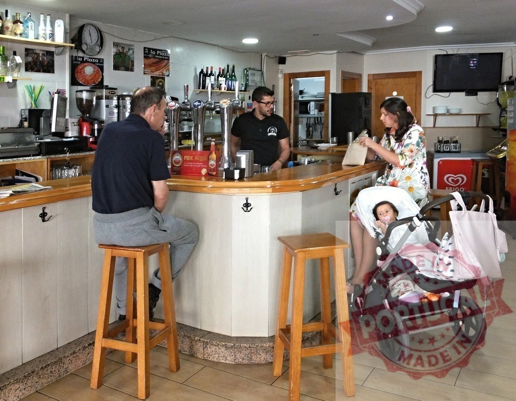 Woman with baby stroller and man at bar counter | Customers enjoying a casual moment at a local bar counter with a bartender serving - Realisiert mit Pictrs.com