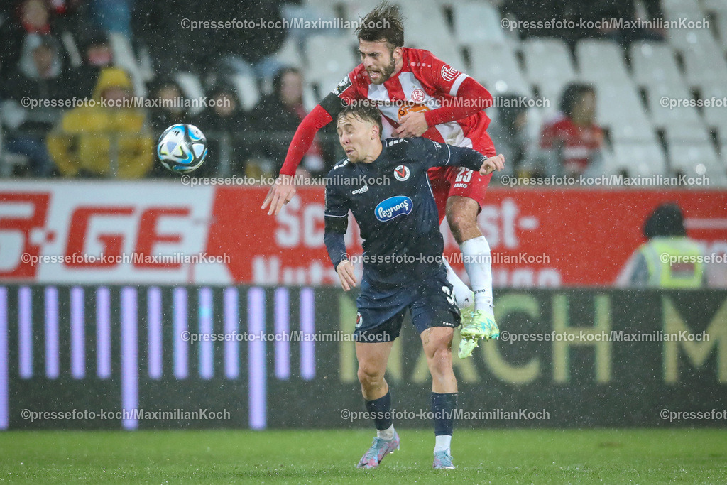 RWE3Liga23012401039 | 23.01.2024, Essen, Fußball, bwin 3. Liga Herren, Stadion an der Hafenstraße, 22. Spieltag Saison 2023 2024, Rot-Weiss Essen – FC Viktoria Köln:  Kopfballduell zwischen Luca Marseiler (Viktoria Köln) und Jose-Enrique Rios-Alonso (Rot-Weiss Essen) im Regen. 
DFB regulations prohibit any use of photographs as image sequences and or quasi-video.