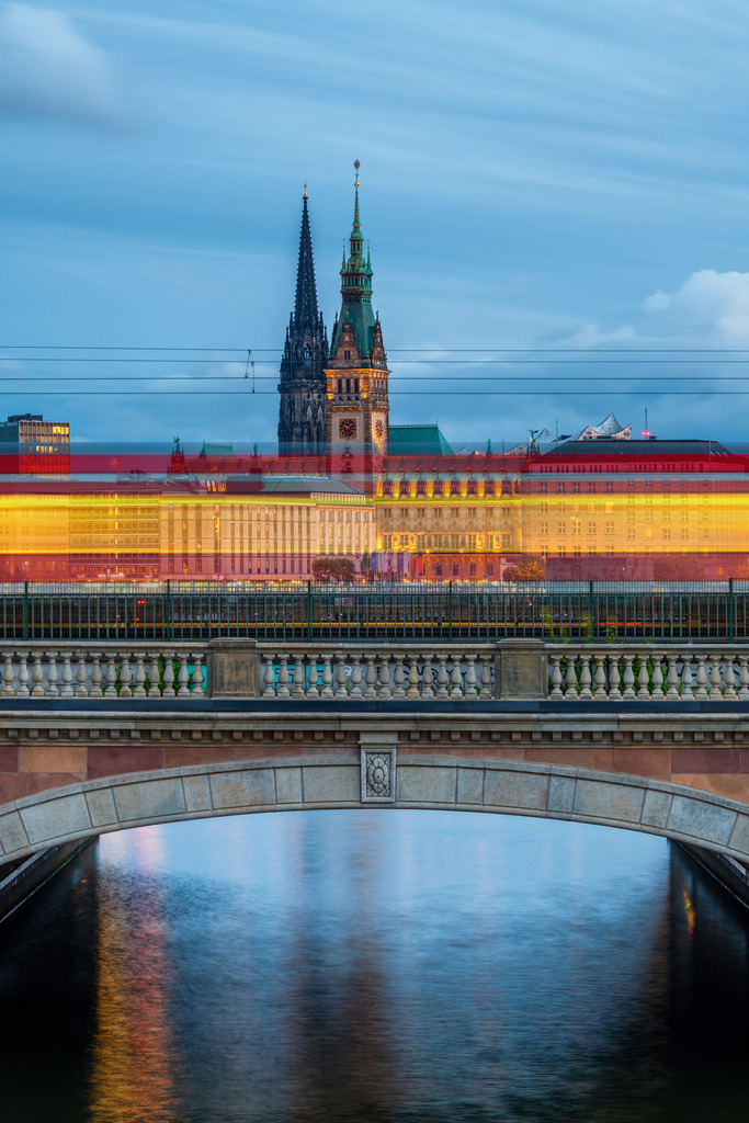 10230903 - S-Bahn und Rathaus | Blick auf die Lombardsbrücke, das Hamburger Rathaus und die Nikolaikirche mit den Lichtstreifen einer vorbeifahrenden S-Bahn.