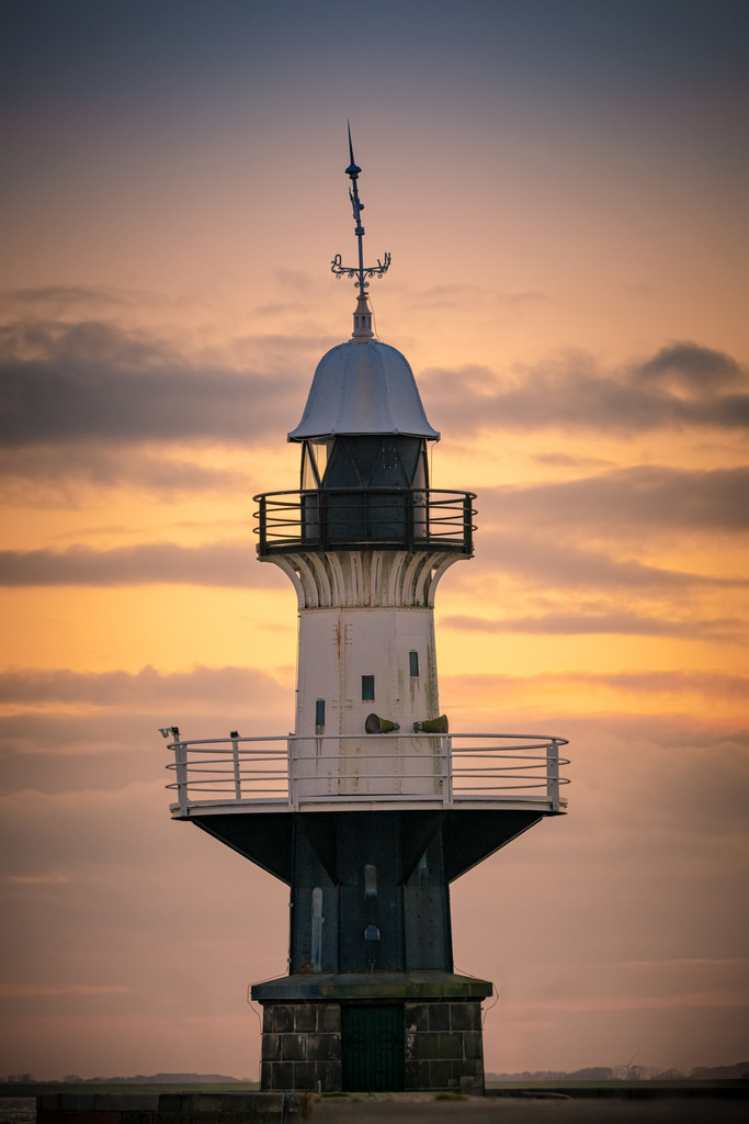 Leuchtturm "Mole 1" Brunsbüttel | Der historische Leuchtturm "Mole 1" in Brunsbüttel präsentiert sich majestätisch vor dem beeindruckenden Hintergrund eines malerischen Sonnenuntergangs. In diesem idyllischen Szenario wird der Leuchtturm "Mole 1" zu einem zeitlosen Symbol der Schifffahrtsgeschichte, das in der malerischen Kulisse eines Sonnenuntergangs seinen ganz eigenen Charme entfaltet.