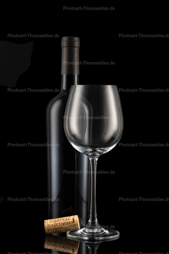 Rotwein Komposition mit Naturkorken auf schwarzem Grund | Diese edle Weinkomposition präsentiert eine dunkle Flasche zusammen mit einem kristallklaren Weinglas und einem beschrifteten Naturkorken. Der schwarze Hintergrund verstärkt die dramatische Wirkung und lässt die glänzenden Oberflächen besonders hervortreten. Der Korken trägt französische Aufschriften und verleiht der Szene Authentizität. Die professionelle Beleuchtung schafft elegante Reflexe auf Glas und Flasche. Ein zeitloses Motiv für Weinliebhaber und stilvolle Küchendekoration. - Realisiert mit Pictrs.com