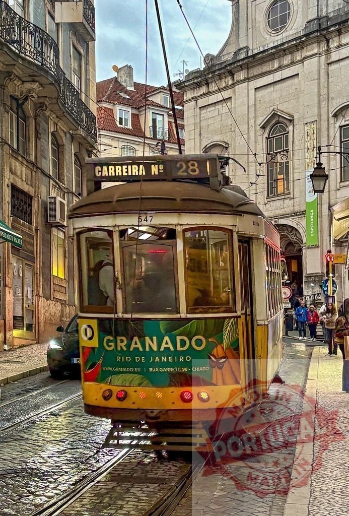 Lisbon tram 28 traveling through Alfama cobblestone street | Iconic yellow tram 28 moving on a narrow, historic street in Lisbon - Realized with Pictrs.com