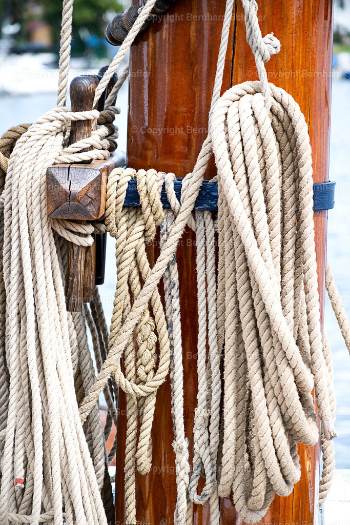 Segeltaue am Mast | Mehrere Seile hängen an den Eisenbeschlägen an einem Mast eines Segelschiffs. - Realisiert mit Pictrs.com