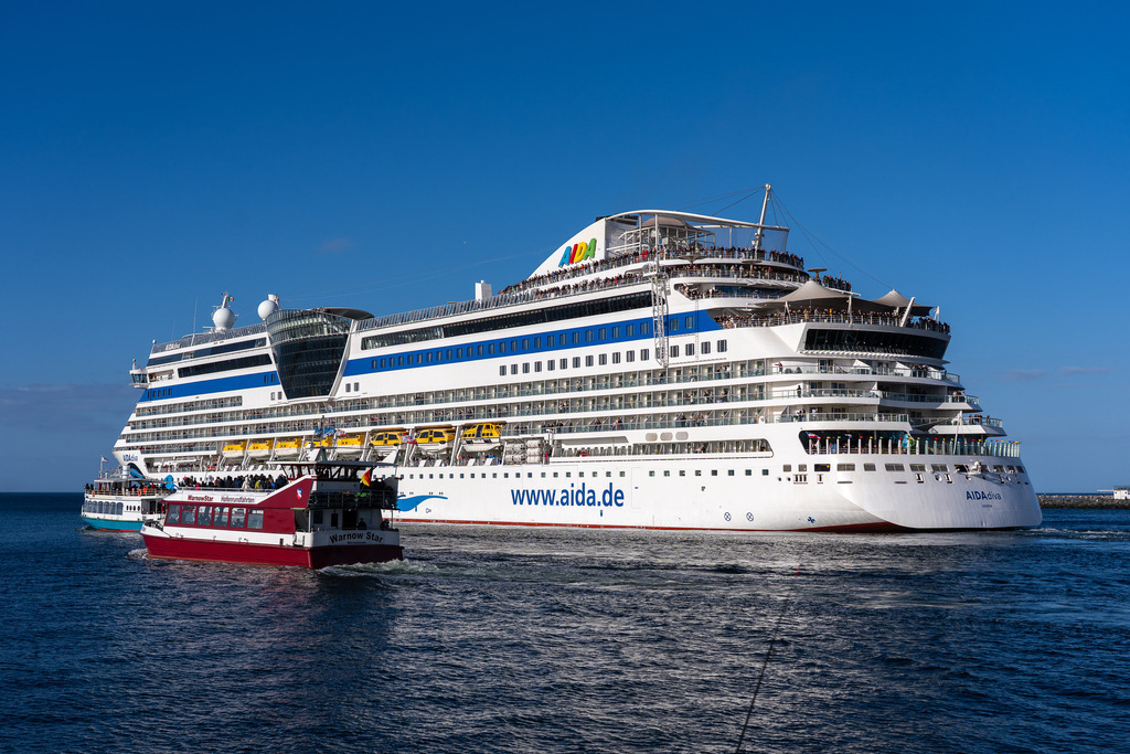 AIDAdiva vor Warnemünde | Das Kreuzfahrtschiff AIDAdiva beim Verlassen des Hafens von Warnemünde mit Kurs auf die offene Ostsee. Die Aufnahme zeigt das Schiff der Sphinx-Klasse in Begleitung des regionalen Fahrgastschiffes Warnow Star, was die enormen Größenunterschiede im Revier verdeutlicht - Realisiert mit Pictrs.com