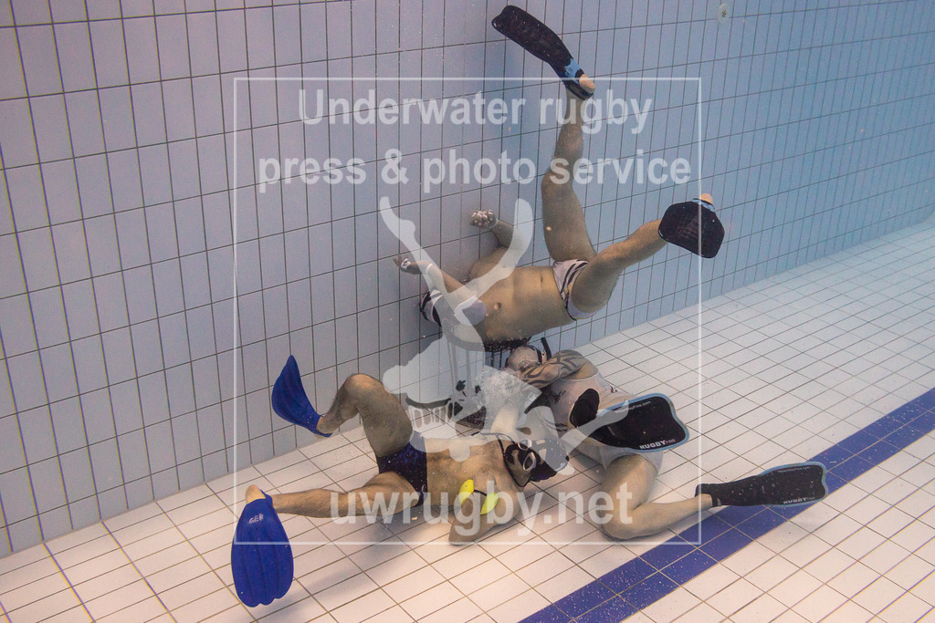 TC Bamberg vs. TSV Malsch, Unterwasser-Rugby, 1. Bundesliga Süd, 5. Spieltag, 2024/2025, 23.03.2025 | TC Bamberg (weiß) vs. TSV Malsch, (blau). Martin Schottmüller (TSV Malsch, #01)  greift das Bamberger Tor an, Michael Nosseir (TC Bamberg, #14) verteidigt unter dem Korb, während der Torwart Sebastian Lange (TC Bamberg, #11) das Tor dicht hält. - Realisiert mit Pictrs.com