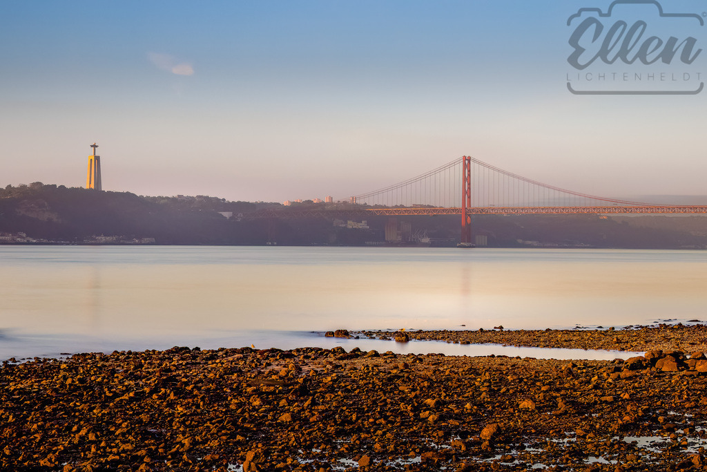 Silent Light of Lisbon | Soft morning light bathes the Tagus River, the bridge and the statue standing in serene harmony. A tranquil moment where the city of Lisbon awakens under a veil of golden calm. - Realisiert mit Pictrs.com