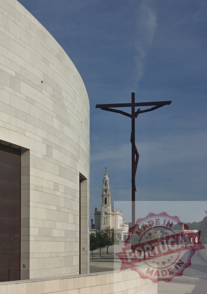 Large crucifix standing in the Sanctuary of Fatima with Basilica of Our Lady of the Rosary in background | Modern building, large crucifix and Basilica of Our Lady of the Rosary under blue sky in Fatima, Portugal - Realisiert mit Pictrs.com