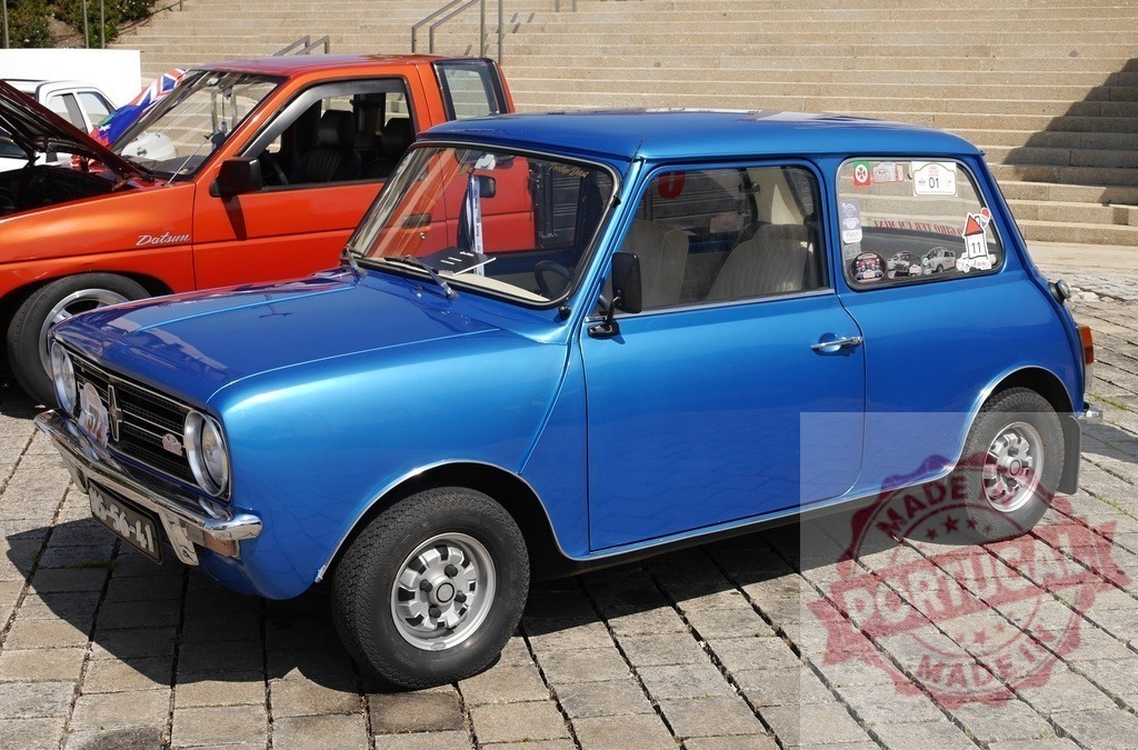 Blue Mini Cooper Clubman classic car on cobblestone | Blue Mini Cooper Clubman classic car parked on cobblestone ground at an outdoor show - Realized with Pictrs.com