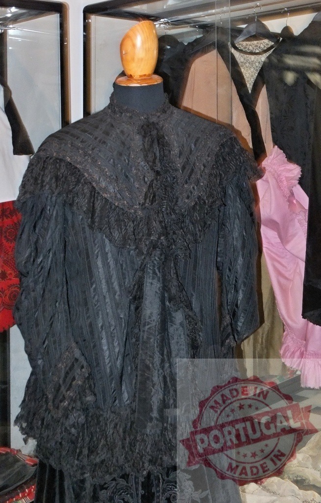 Vintage black dress costume on mannequin in museum display | Elaborate black Victorian-era dress with lace and ruffles displayed on a mannequin - Realized with Pictrs.com