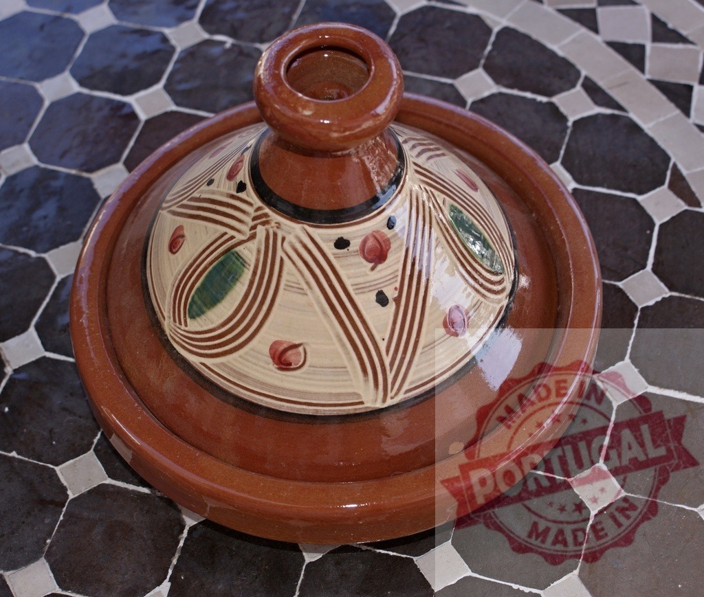 Moroccan clay tagine pot on tiled table | Traditional Moroccan earthenware tagine pot sitting on a decorative tiled surface - Realized with Pictrs.com
