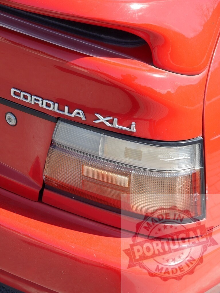 Red Toyota Corolla XLi car rear with spoiler | Red Toyota Corolla XLi car's rear showing taillight, bumper, and spoiler in sunlight - Realized with Pictrs.com