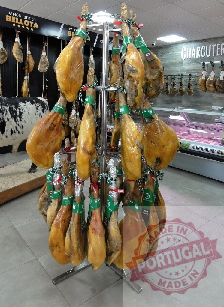 Jamón Ibérico bellota legs hanging in charcuterie shop | Cured ham legs hanging on a display stand in a charcuterie shop or market - Realized with Pictrs.com