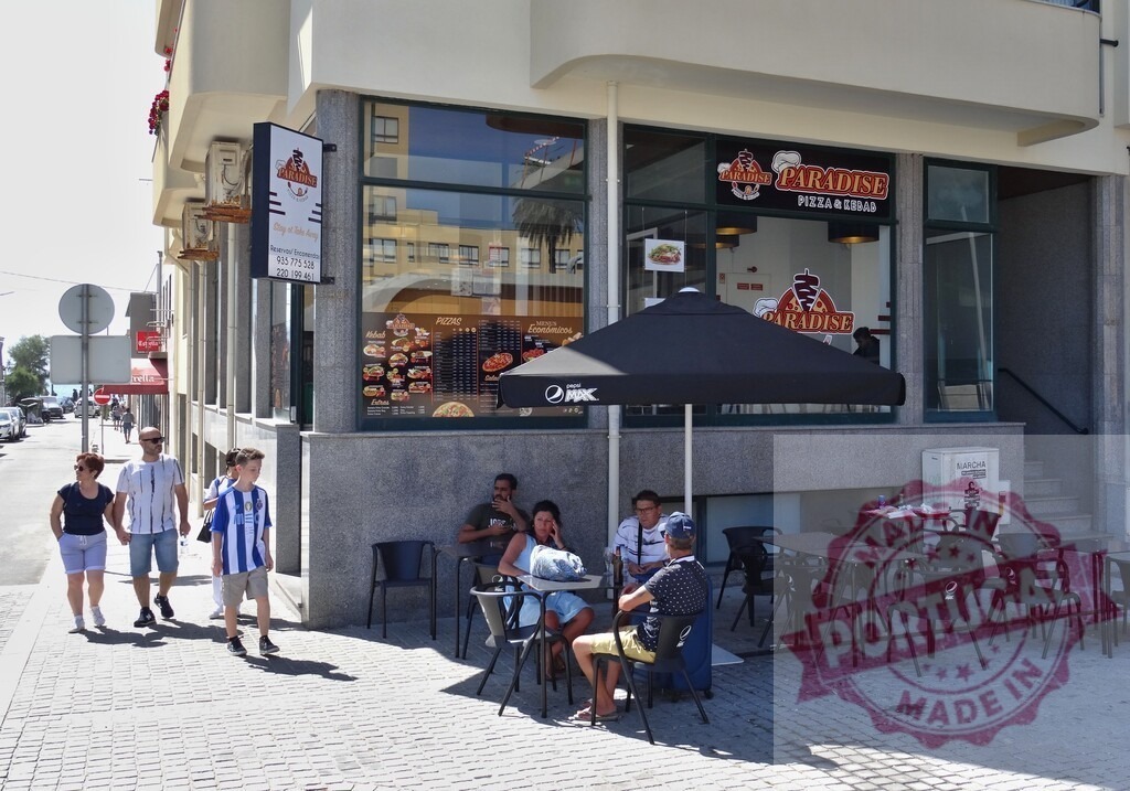 People enjoying outdoor seating at Paradise Pizza & Kebab | People relaxing and eating at a fast food restaurant with outdoor seating on a sunny day - Realisiert mit Pictrs.com