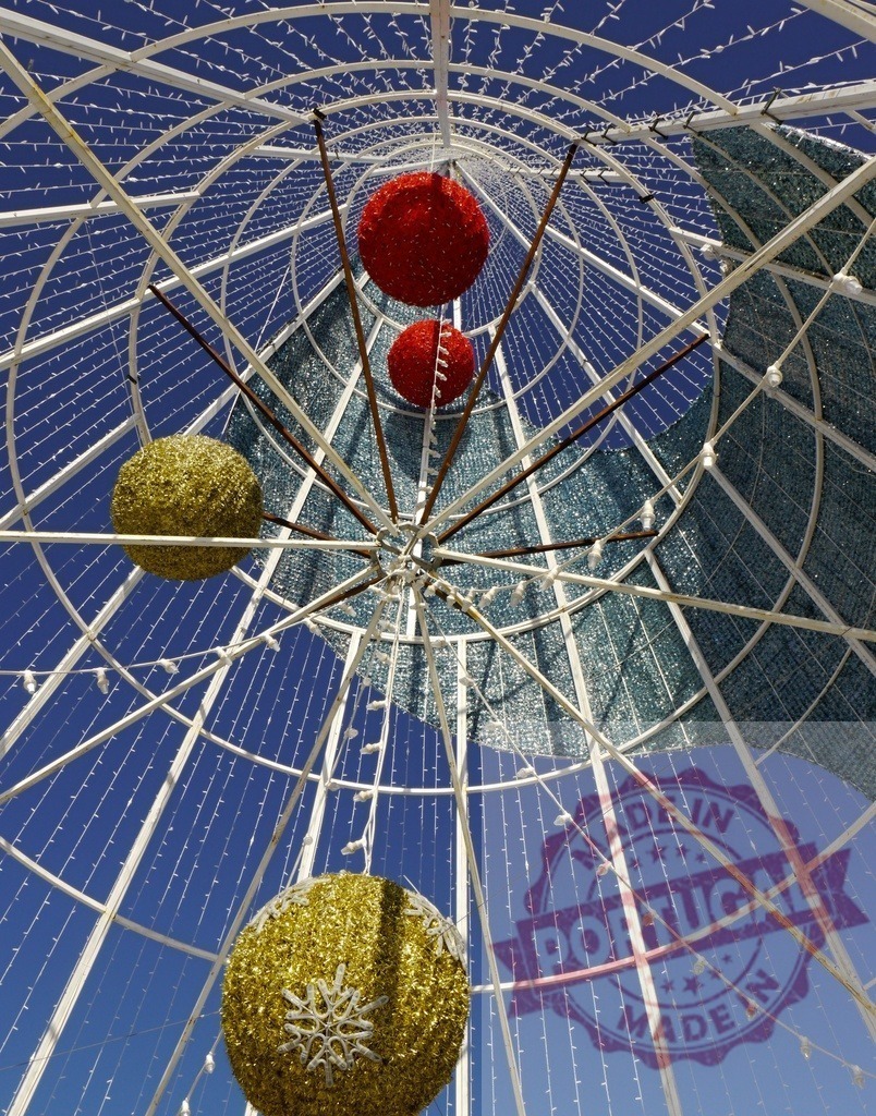 Giant christmas tree metal structure with red and gold balls decorating against blue sky | Low angle view of giant christmas tree metal structure with red and gold balls decorating against blue sky - Realized with Pictrs.com