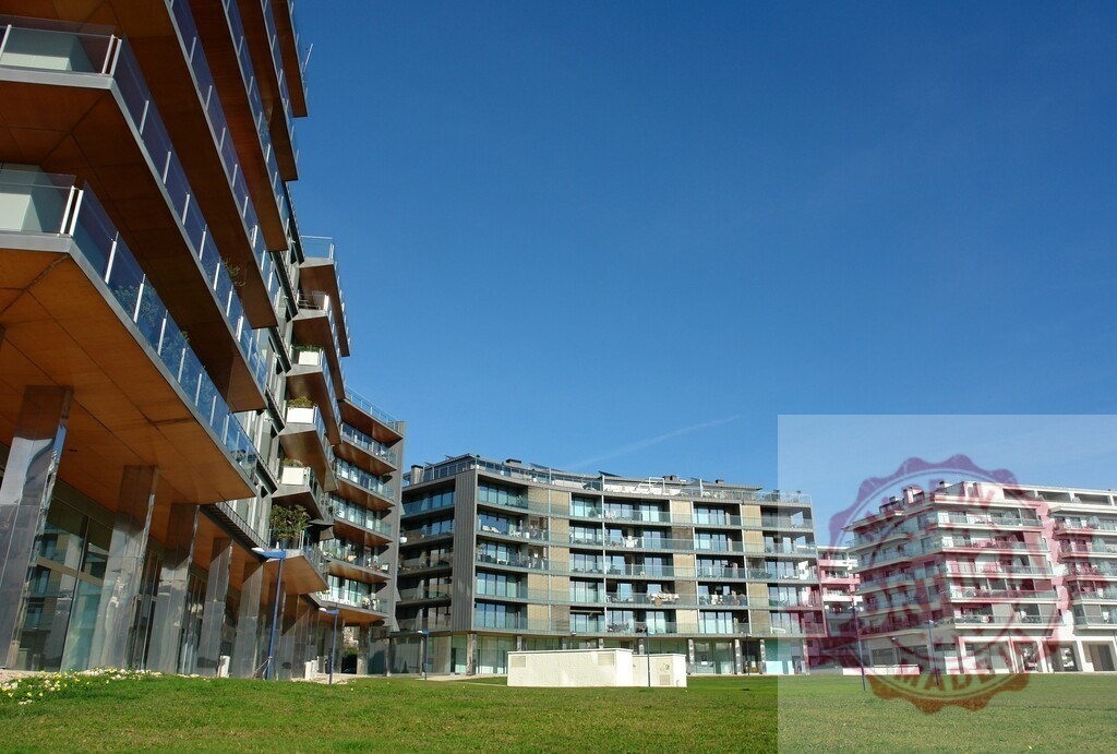 Modern residential apartment buildings with green grass area | Contemporary apartment complexes featuring balconies and a clear blue sky over a green lawn - Realized with Pictrs.com