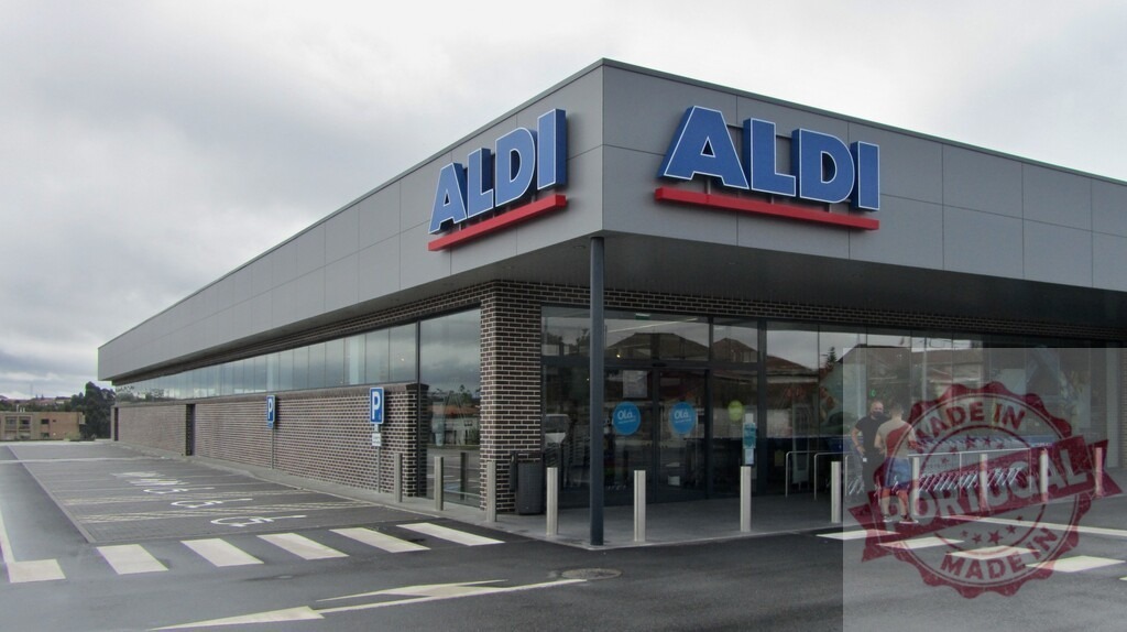Aldi supermarket building exterior with parking lot | Aldi supermarket facade showing the entrance, parking area, and carts on a cloudy day - Realized with Pictrs.com