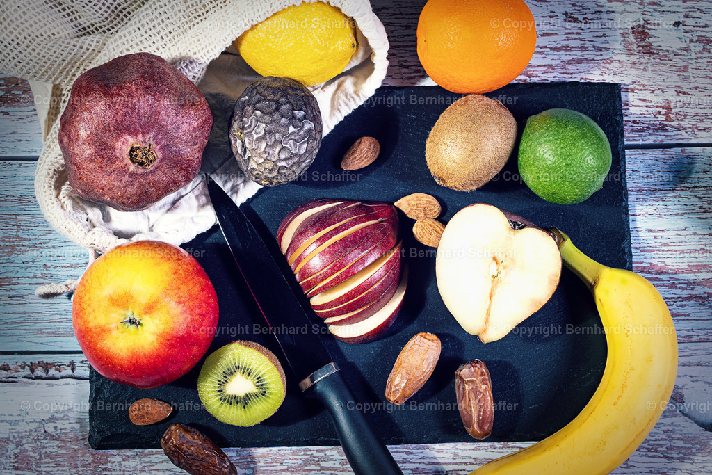 Obstmix auf Schnittplatte | Eine Platte mit verschiedenen Obstsorten für die Zubereitung eines Obstsalats. - Realisiert mit Pictrs.com