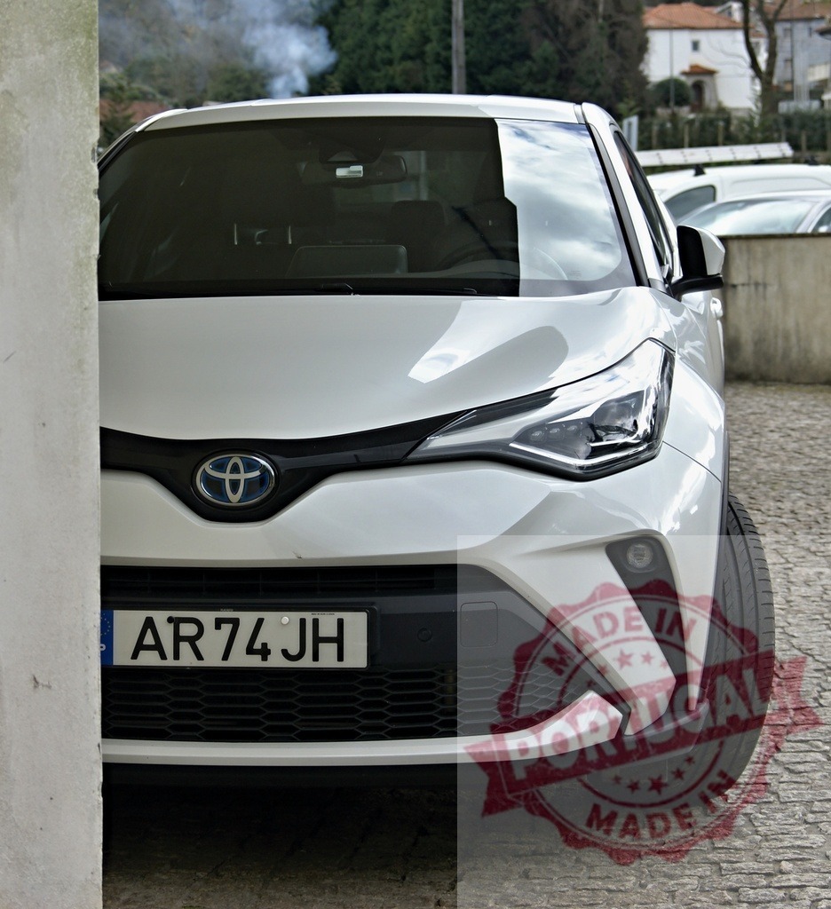 White Toyota C-HR parked on a cobblestone street | White Toyota C-HR hybrid car at front view with Portuguese license plate and modern design - Realized with Pictrs.com
