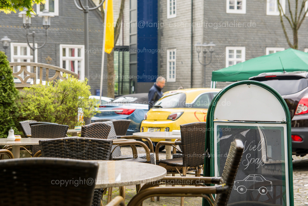 Autosalon in Brilon | In Brilon, Deutschland findet eine Ausstellung für Autos auf dem Marktplatz statt. Im Vordergrund ist ein Cafe mit einem Schild, auf dem deutscher Text steht: Viel Spaß. 