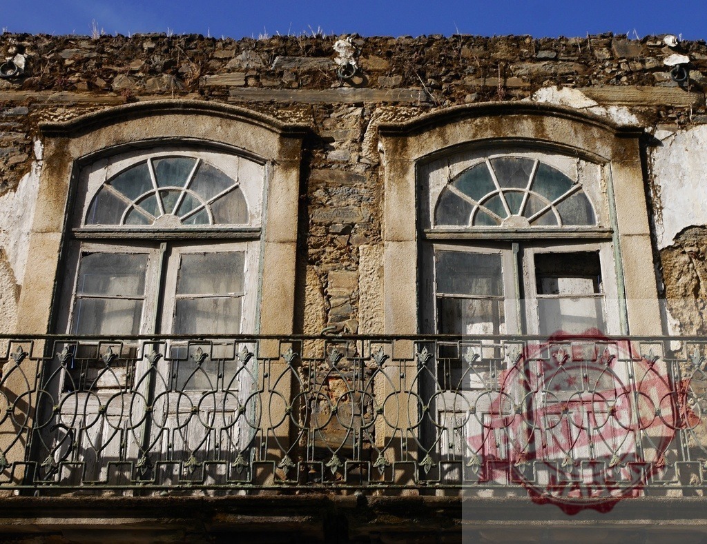 Abandoned building windows showing decay and weathered facade | Abandoned building facade featuring old windows and a wrought iron balcony under blue sky - Realisiert mit Pictrs.com