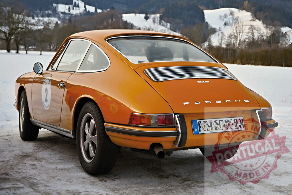 Orange Porsche 911 vintage rally car in snow | Orange Porsche 911 coupe parked on snow-covered ground with number 2 on side - Realized with Pictrs.com
