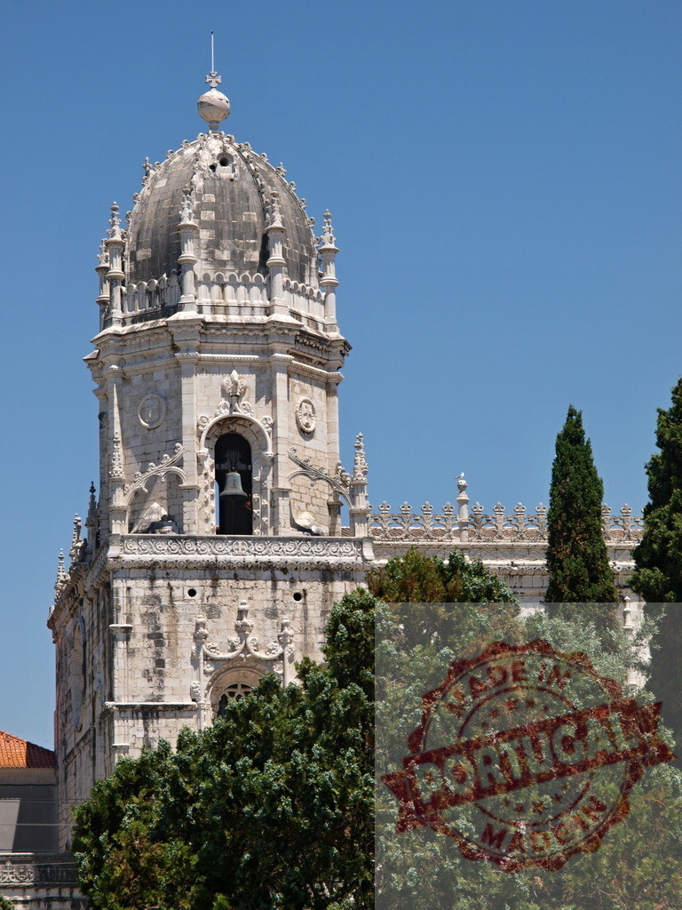 Jeronimos Monastery tower with bell against blue sky. Lisbon - Portugal | Jeronimos Monastery dome and tower with bell, surrounded by green trees on a sunny day - Realisiert mit Pictrs.com