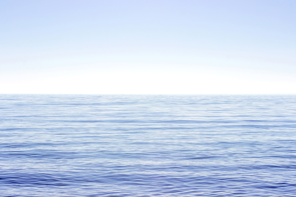 Stille Wasserlinie – Minimalistische Küstenfotografie | Ein ruhiger Wasserstreifen unter einem klaren Himmel, reduziert auf Licht, Weite und absolute Gelassenheit. Die sanften Bewegungen der Oberfläche und die klare Horizontlinie erzeugen eine stille Spannung, die den Blick fesselt und gleichzeitig beruhigt. Dieses minimalistische Küstenmotiv bringt eine zeitlose, elegante Ruhe in moderne Wohnräume und schafft einen visuellen Rückzugsort voller Klarheit. Die reduzierte Komposition wirkt besonders edel in puristischen Interiors und setzt einen feinen, hochwertigen Akzent im gehobenen Wanddesign.