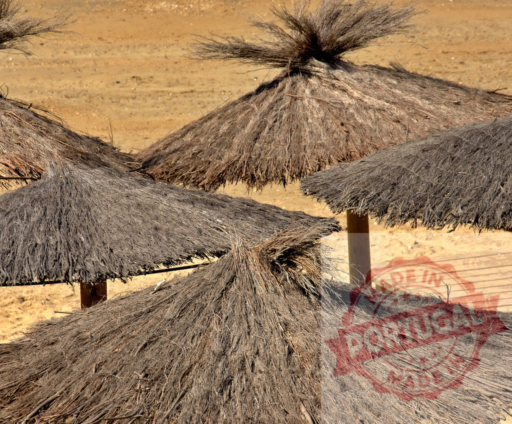Thatched umbrellas providing shade on sandy beach. Espana - Cadiz | Thatched umbrellas creating relaxing shade for summer beachgoers - Realized with Pictrs.com