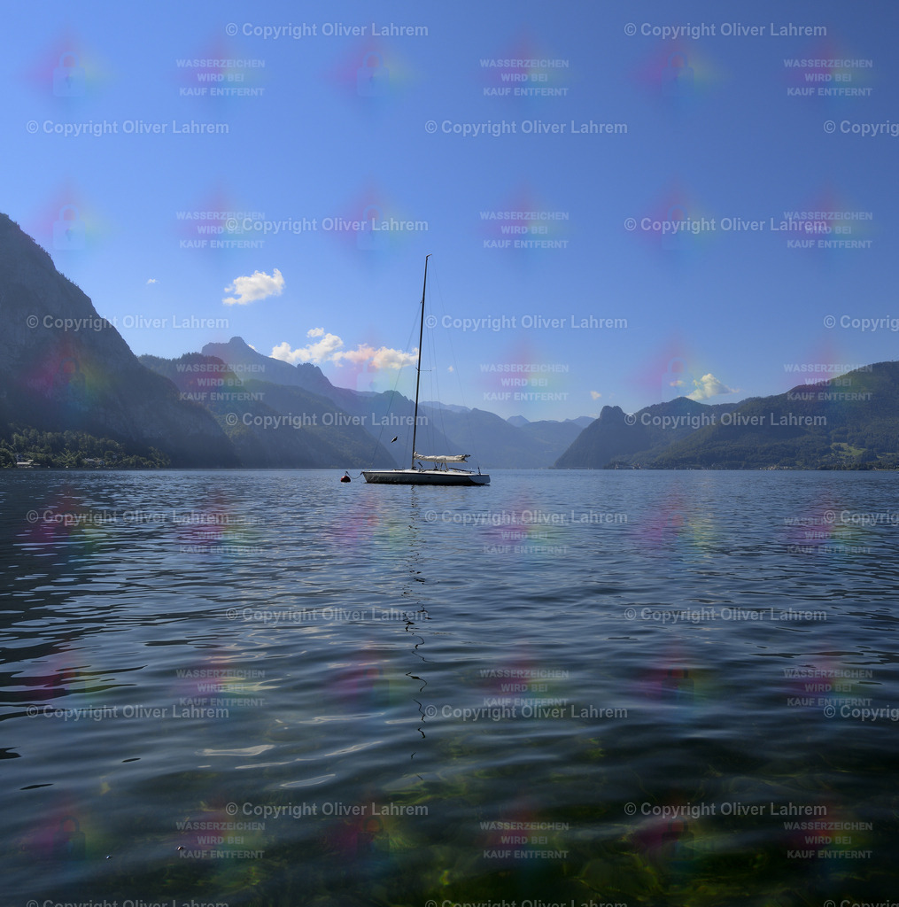 Ein Segelboot auf dem Traunsee | Ein Segelboot ankert mitten auf dem klaren Traunsee im Sonnenschein und im Hintergrund sind die Berge zu sehen.