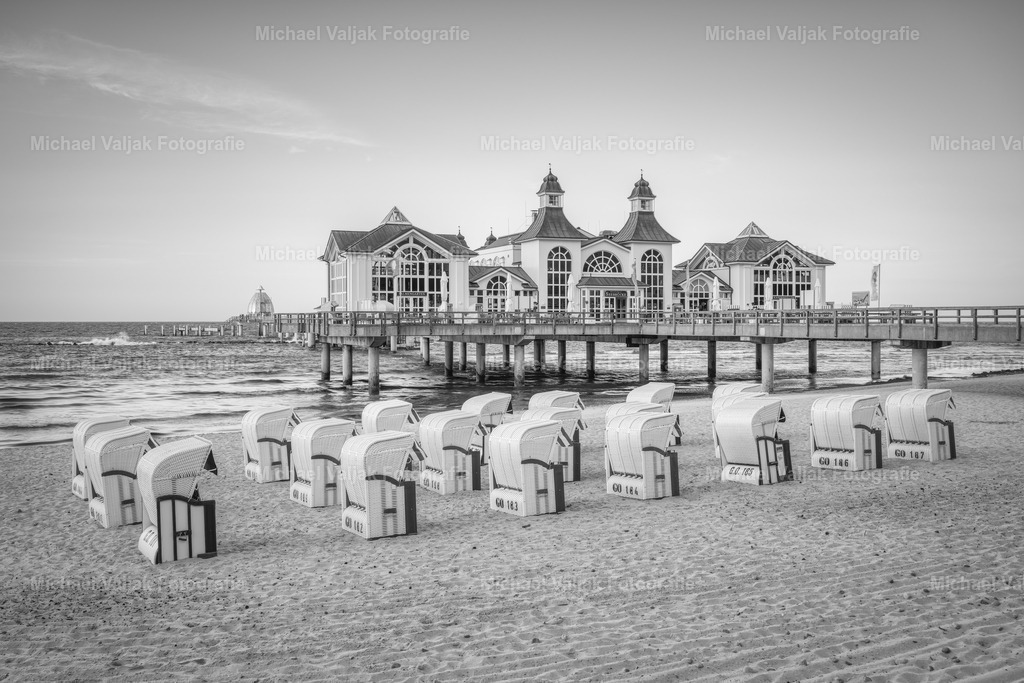 Seebrücke Sellin auf Rügen schwarz-weiß | Die Seebrücke Sellin ist eine der bekanntesten Attraktionen auf der Insel Rügen. Sie wurde ursprünglich im Jahr 1906 erbaut und ist heute ein beliebtes Fotomotiv. Die Seebrücke ist 394 Meter lang und beherbergt ein Restaurant im Stil der Bäderarchitektur. Die schwarz-weiße Fotografie verleiht der Seebrücke einen nostalgischen Charme und betont die Kontraste zwischen dem Meer, dem Himmel und dem Holz. Die Seebrücke Sellin ist ein Zeugnis der Geschichte und Kultur Rügens und lädt zum Spazieren, Genießen und Entspannen ein. - Realisiert mit Pictrs.com