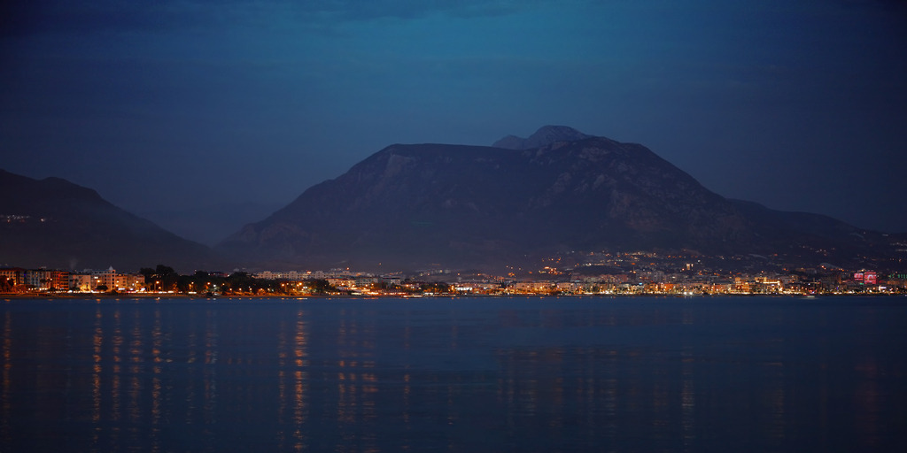 Alanya bei Nacht, Türkei | Das Bild zeigt einen nächtlichen Blick auf die Küstenstadt Alanya im Süden der Türkei. Der beliebte Urlaubsort an der türkischen Riviera strahlt vor einer Bergkette und hellt den tiefblauen Nachthimmel durch seine warmen, funkelnden Lichtern auf, die vom ruhigen Wasser des Mittelmeers sanft reflektiert werden. Die Szene strahlt eine ruhige Eleganz aus und vermittelt den Charme dieser lebendigen Stadt bei Nacht.Unsere Empfehlung: Acrylglas - Realisiert mit Pictrs.com