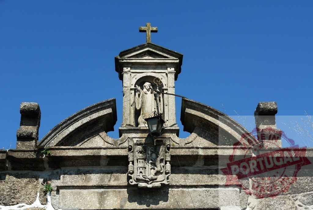 Stone saint statue on old religious building. Region Norte - Portugal | Stone statue of a saint crowning a historical church building against a blue sky - Realisiert mit Pictrs.com