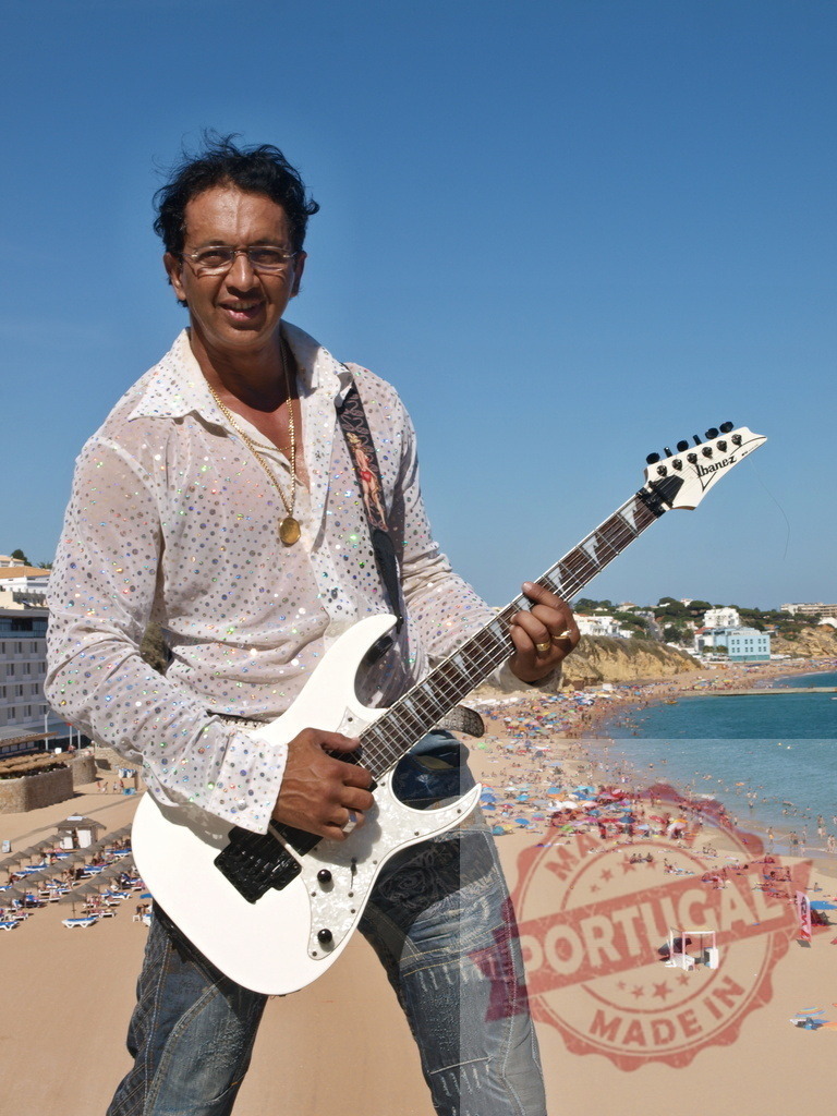 Musician playing electric guitar on beach in Algarve, Portugal | Guitarist playing electric guitar with Praia da Rocha beach in the background - Realized with Pictrs.com