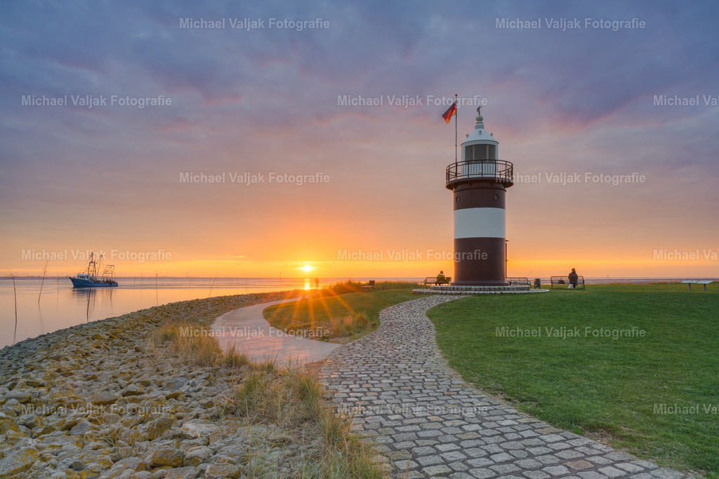 Leuchtturm Kleiner Preuße bei Sonnenuntergang | Das Bild zeigt den Kleinen Preußen in Wremen in einer ruhigen Abendstimmung. Links fährt ein Kutter langsam aus dem Bild, während die Sonne mittig als Sonnenstern erscheint – kurz bevor sie hinter dem Horizont verschwindet. Rechts steht der Leuchtturm, klar erkennbar vor dem warmen Licht des Himmels.Die Aufnahme verbindet maritime Elemente mit einem natürlichen Lichtmoment und bietet einen typischen Blick auf die Nordseeküste bei Tagesende. - Realisiert mit Pictrs.com