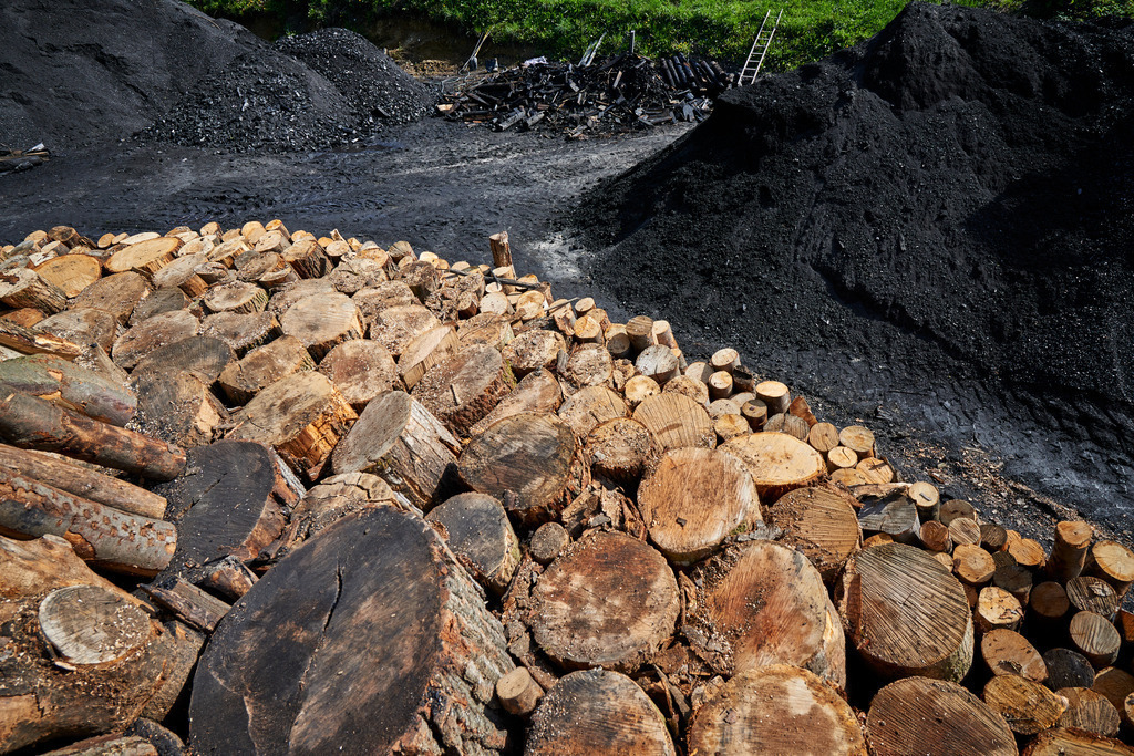 Blick vom Kohlmeiler auf den Köhlerplatz | Michelbach, Austria - May 08, 2019: Waldköhlerei Hochecker, die 2011 in das Nationale Verzeichnis des immateriellen Kulturerbes der UNESCO aufgenommen wurde, produziert noch echte Holzkohle; Blick vom Kohlmeiler auf den Köhlerplatz. - Realisiert mit Pictrs.com